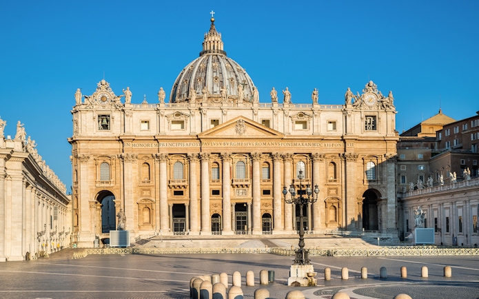 St. Peter's Basilica facade in Vatican City under clear blue sky.