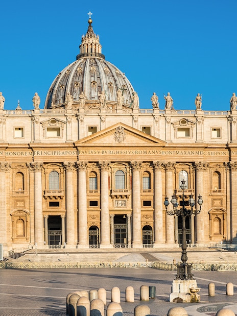 St. Peter's Basilica facade in Vatican City under clear blue sky.
