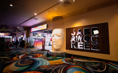 Entrance to Jabbawockeez show in Las Vegas with large mask sculpture and colorful carpet.