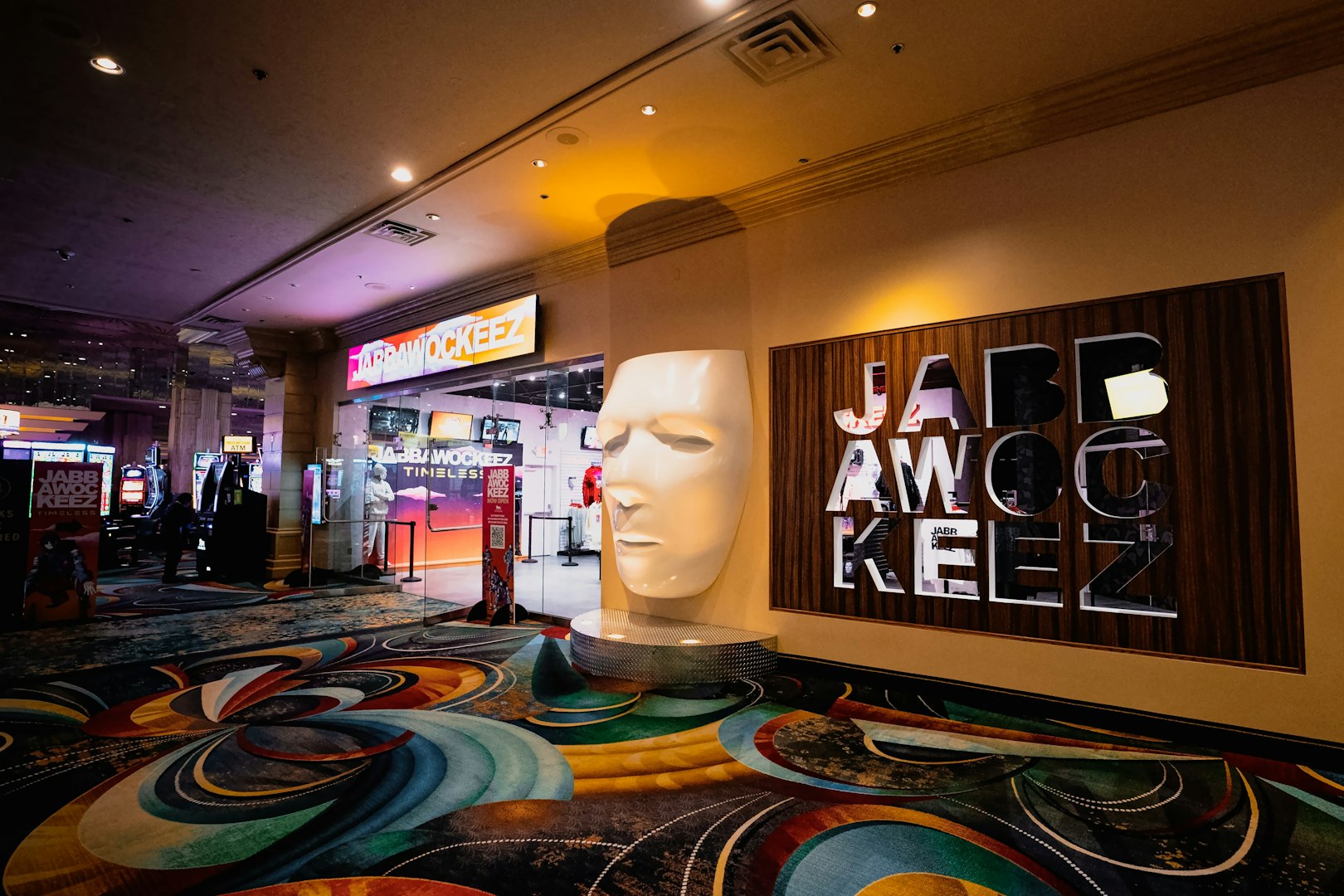 Entrance to Jabbawockeez show in Las Vegas with large mask sculpture and colorful carpet.
