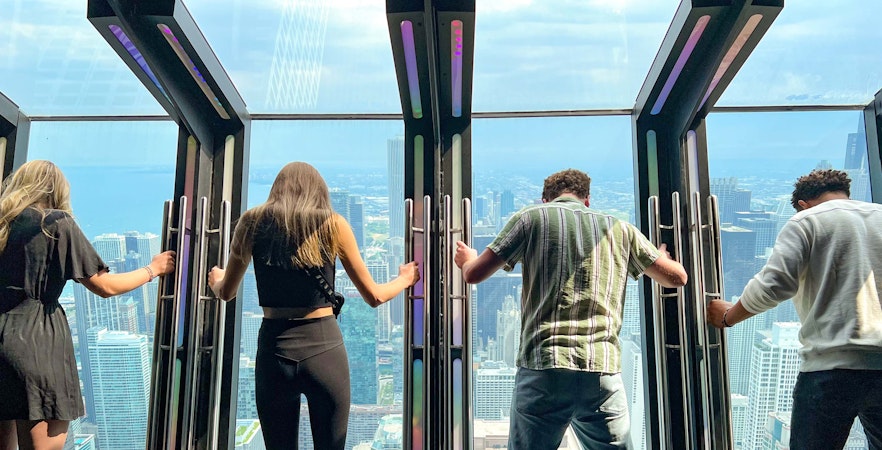 Visitors experiencing Tilt at 360 Chicago Observation Deck with city skyline view.