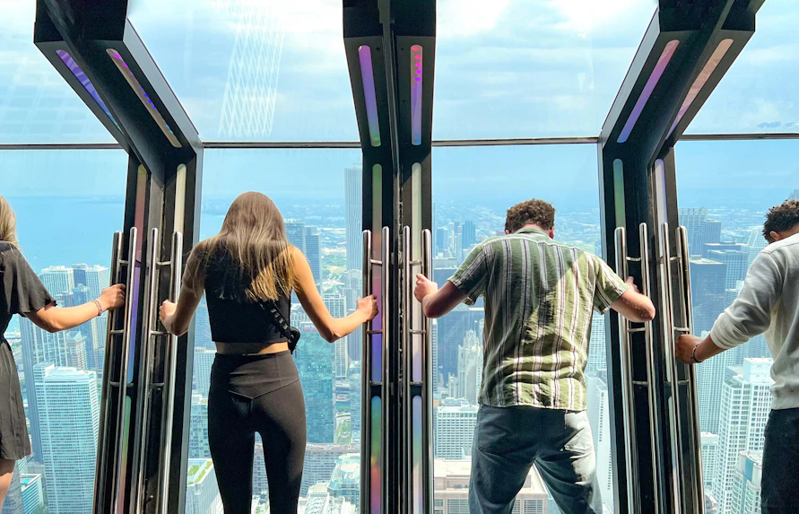 Visitors experiencing Tilt at 360 Chicago Observation Deck with city skyline view.