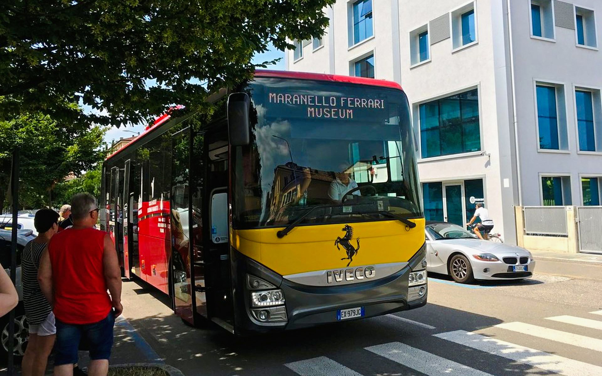 Bus transfer at Modena Ferrari Museum with people boarding.