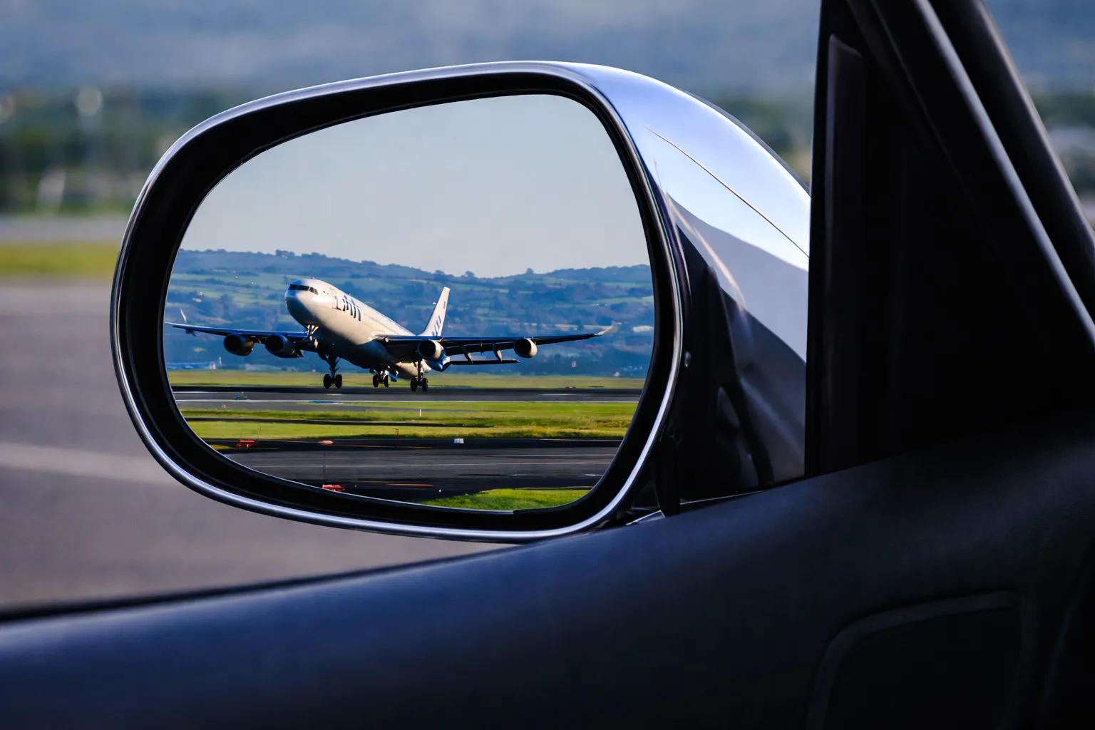 Airplane on runway seen in car mirror during Florence airport transfer.