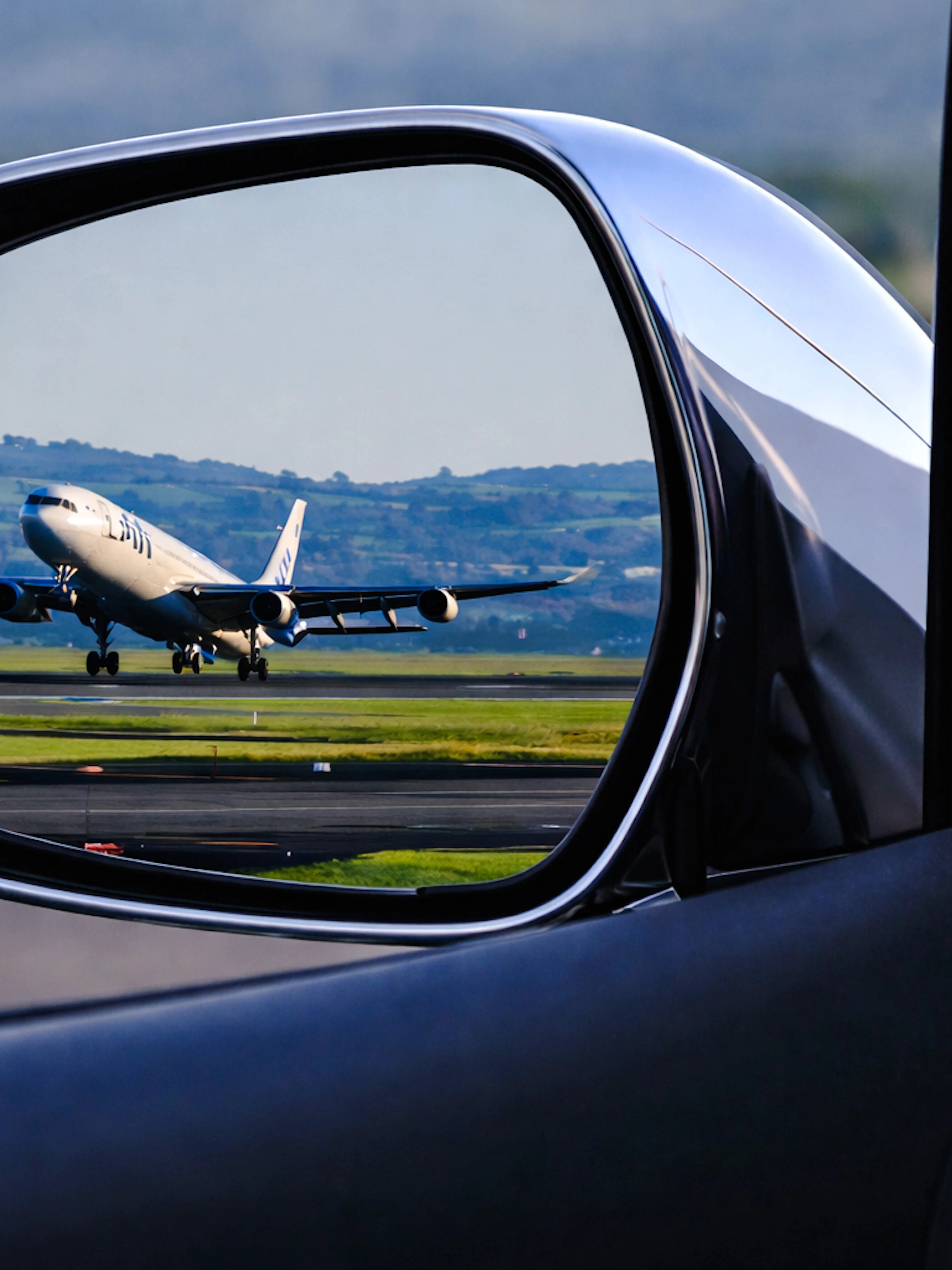 Airplane on runway seen in car mirror during Florence airport transfer.