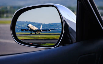 Airplane on runway seen in car mirror during Florence airport transfer.