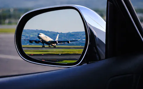 Airplane on runway seen in car mirror during Florence airport transfer.