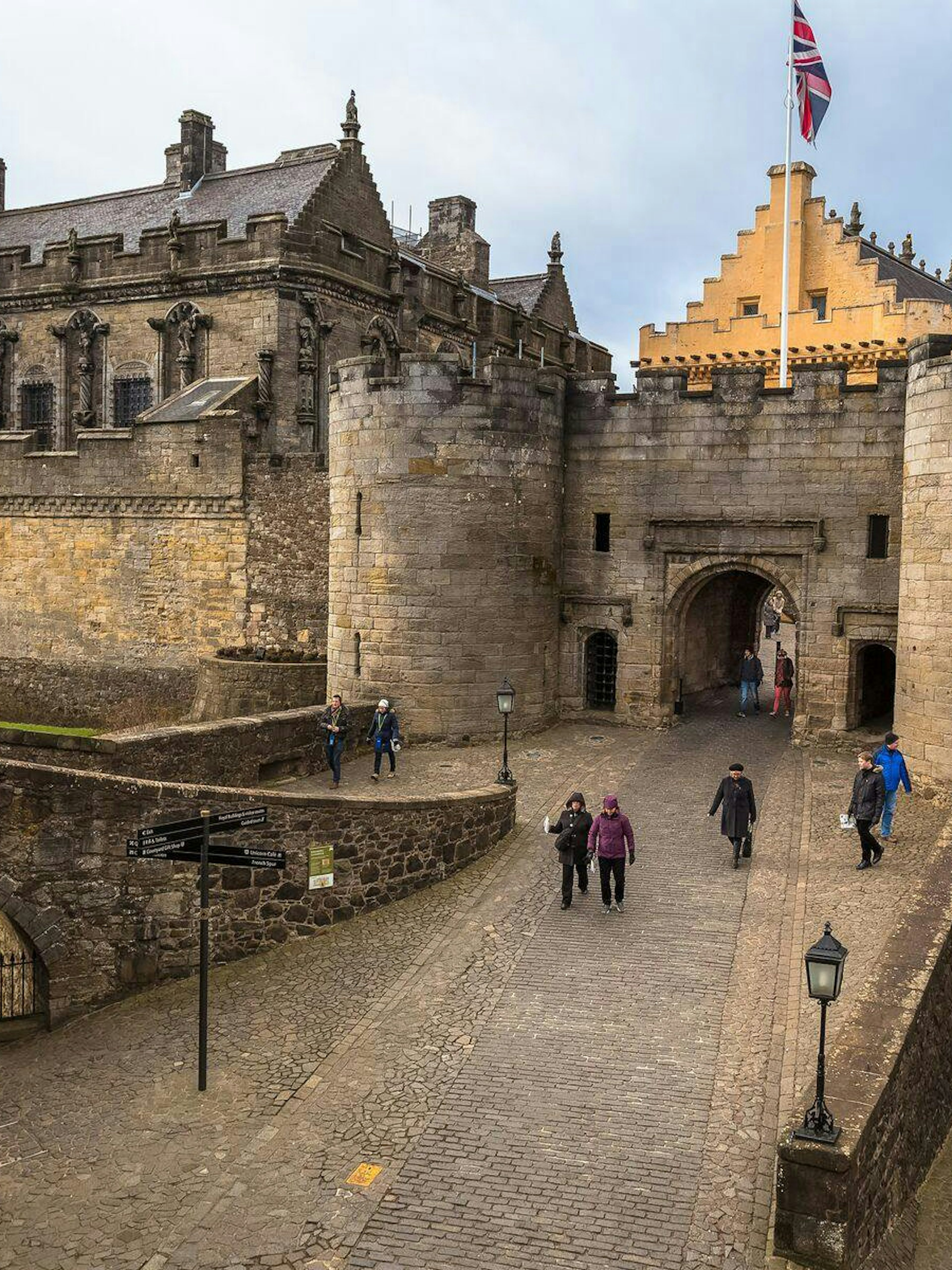 Stirling Castle entrance with visitors walking on cobblestone path, Scotland.