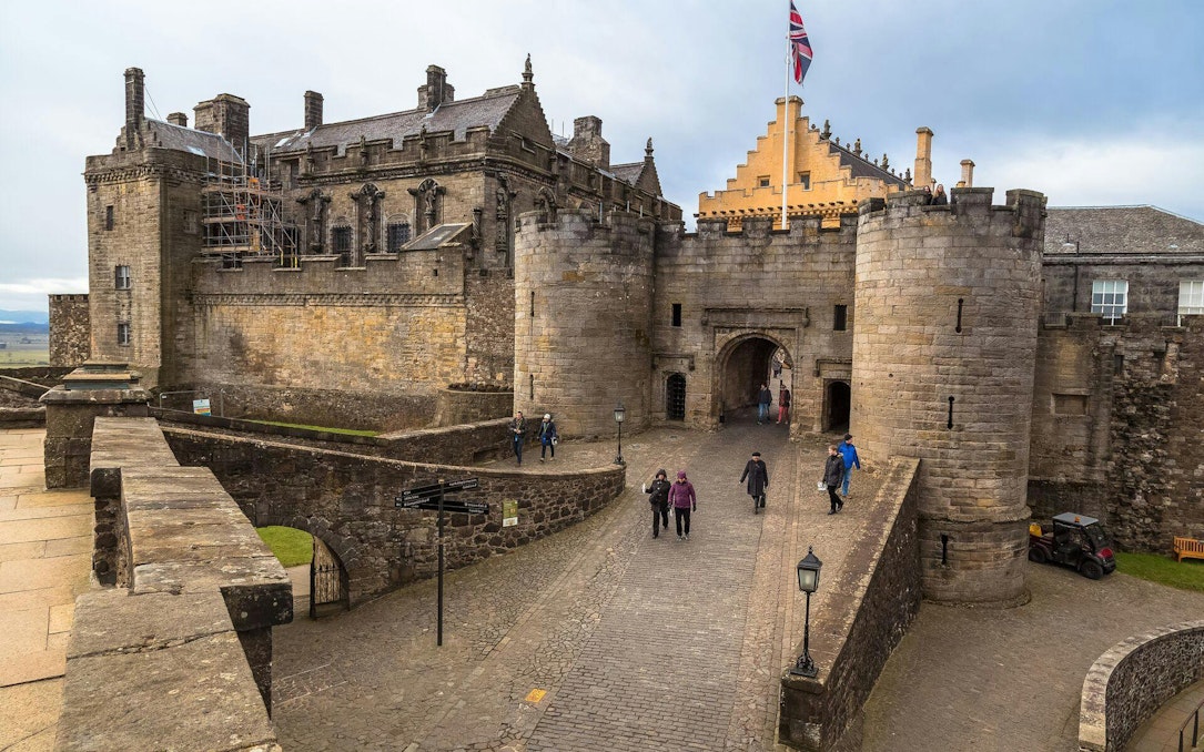 Stirling Castle entrance with visitors walking on cobblestone path, Scotland.
