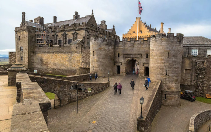 Stirling Castle entrance with visitors walking on cobblestone path, Scotland.