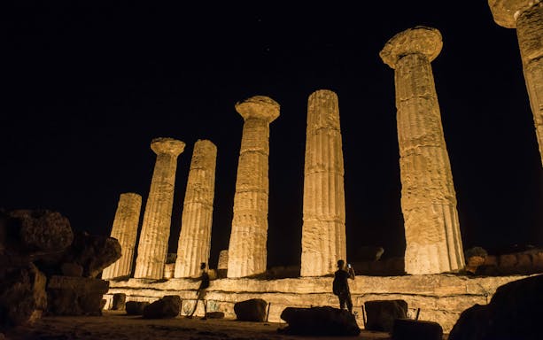 Ancient temple columns illuminated at night in Agrigento, Sicily, Italy.