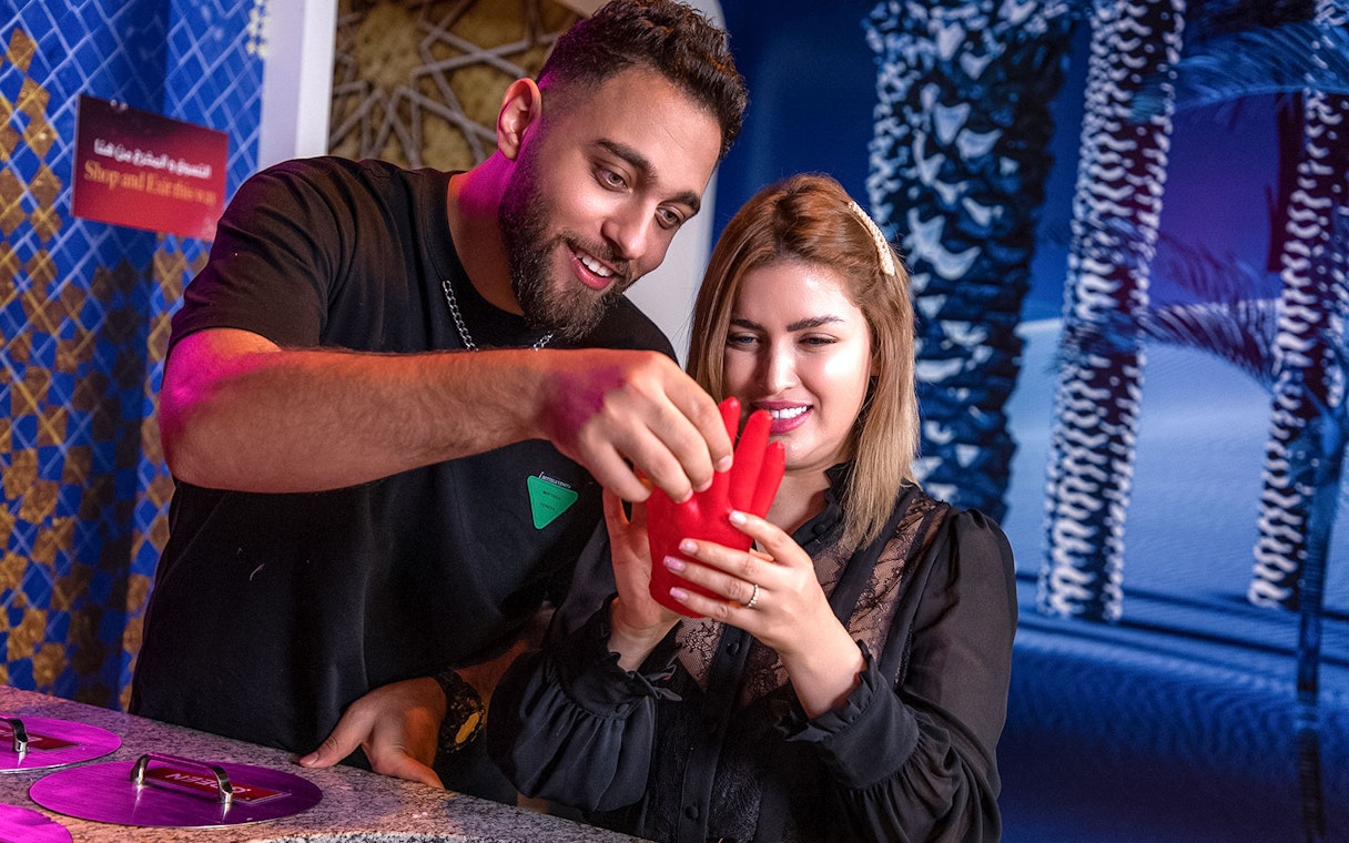 Couple creating wax hand mold at Madame Tussauds Dubai experience.