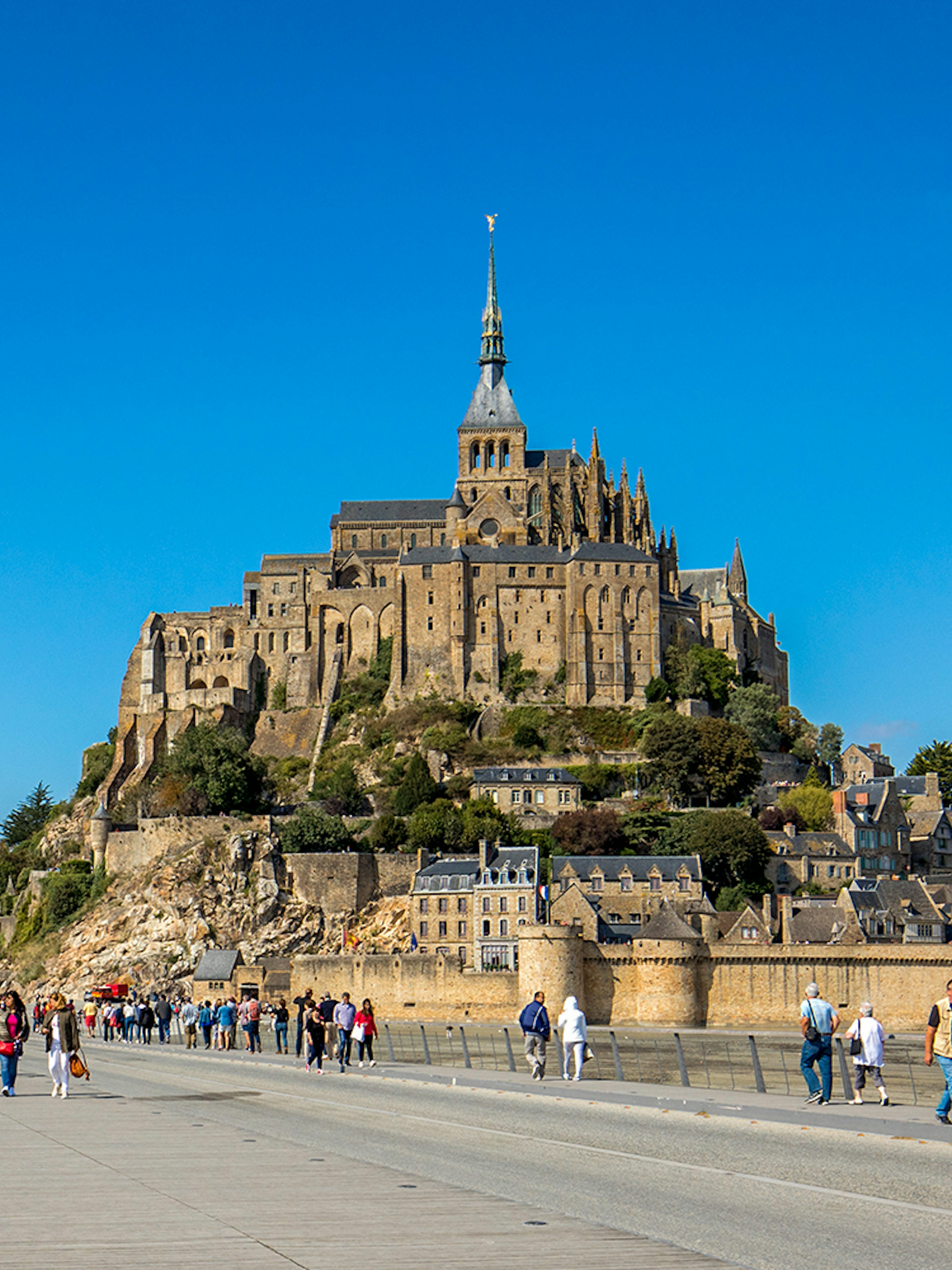 Visitors walking towards Mont-Saint-Michel Abbey in Normandy, France.