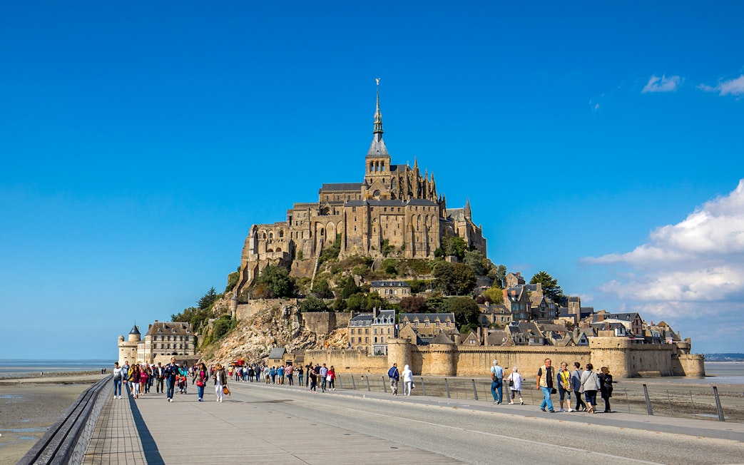 Visitors walking towards Mont-Saint-Michel Abbey in Normandy, France.
