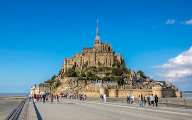 Visitors walking towards Mont-Saint-Michel Abbey in Normandy, France.