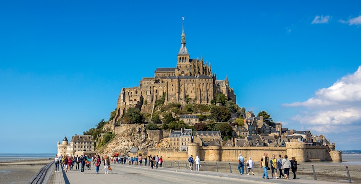 Visitors walking towards Mont-Saint-Michel Abbey in Normandy, France.