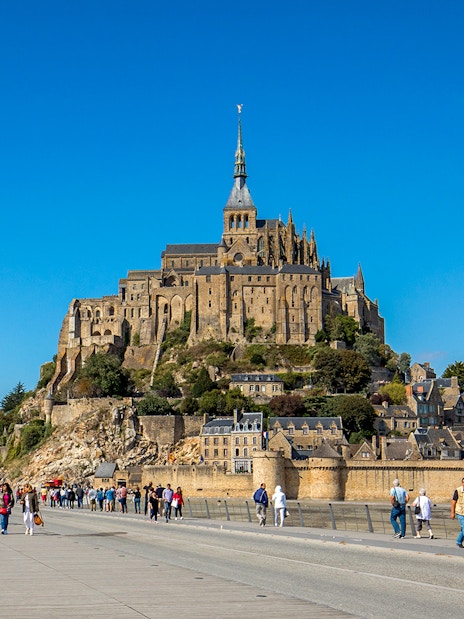 Visitors walking towards Mont-Saint-Michel Abbey in Normandy, France.