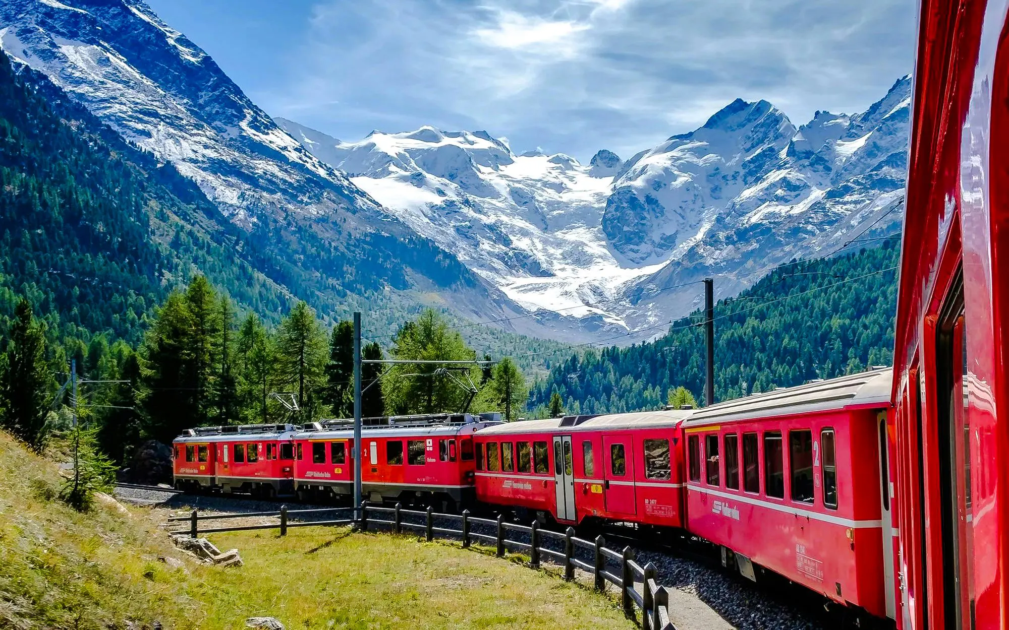 Red train traveling through alpine landscape near Neuschwanstein Castle on a small group day trip.