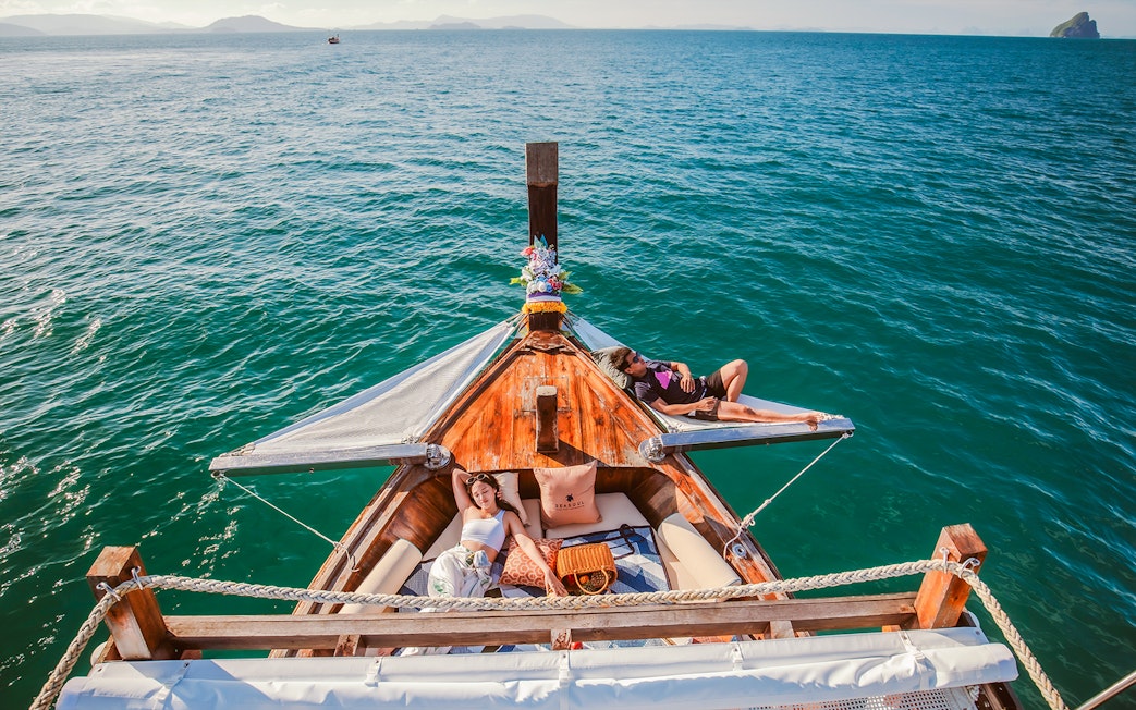 Luxury longtail boat cruise at sunset in Krabi with people relaxing.