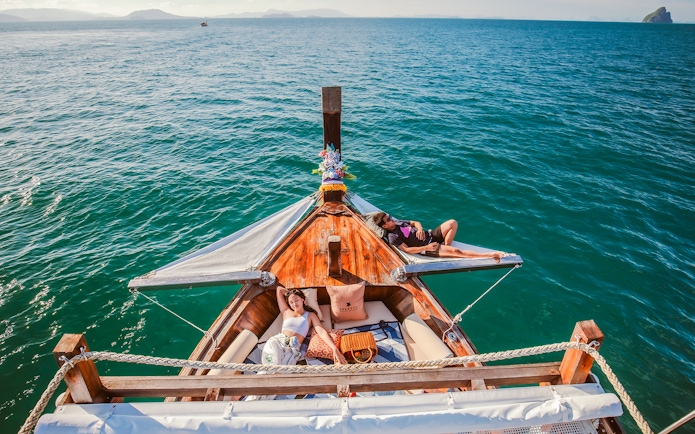 Luxury longtail boat cruise at sunset in Krabi with people relaxing.