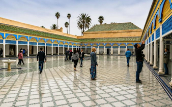 Visitors exploring the courtyard of Bahia Palace in Marrakech's Medina.