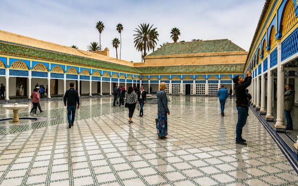 Visitors exploring the courtyard of Bahia Palace in Marrakech's Medina.