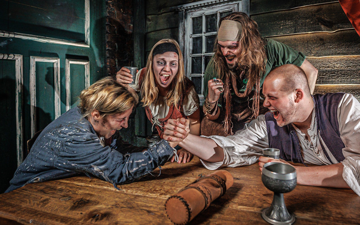 Visitors arm wrestling in a themed room at Hamburg Dungeon.