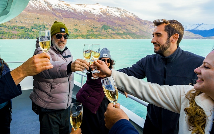 Tourists toasting with champagne on a cruise boat near Perito Moreno Glacier, Argentina.