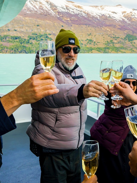 Tourists toasting with champagne on a cruise boat near Perito Moreno Glacier, Argentina.