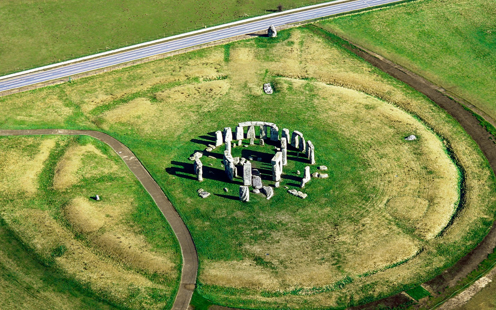 Aerial view of Stonehenge with surrounding landscape and The Avenue path visible.