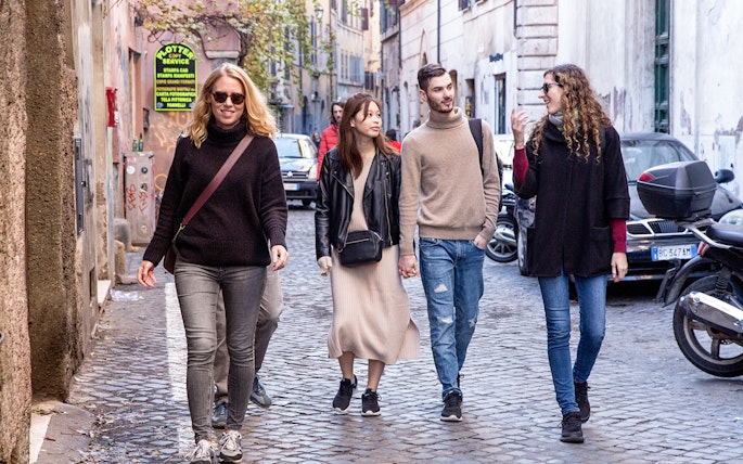 Friends walking on a cobblestone street in Rome, Italy.