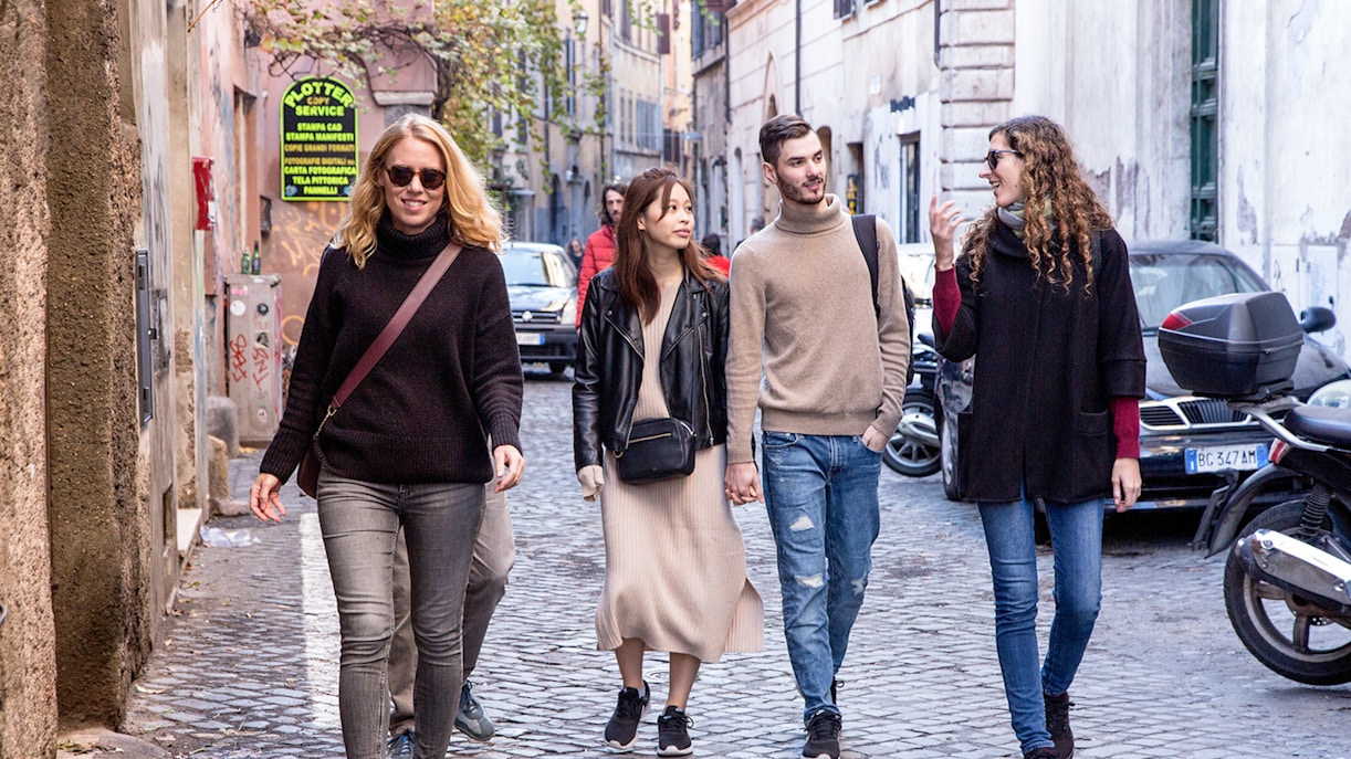 Friends walking on a cobblestone street in Rome, Italy.