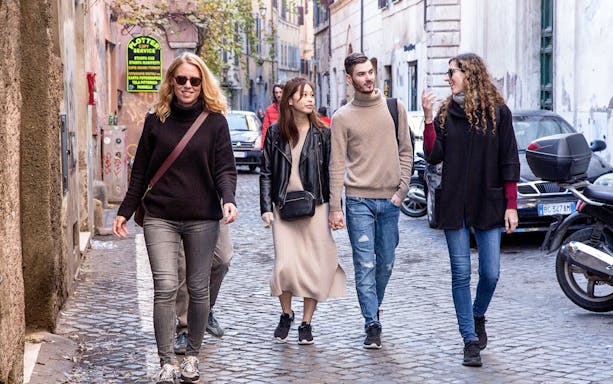 Friends walking on a cobblestone street in Rome, Italy.