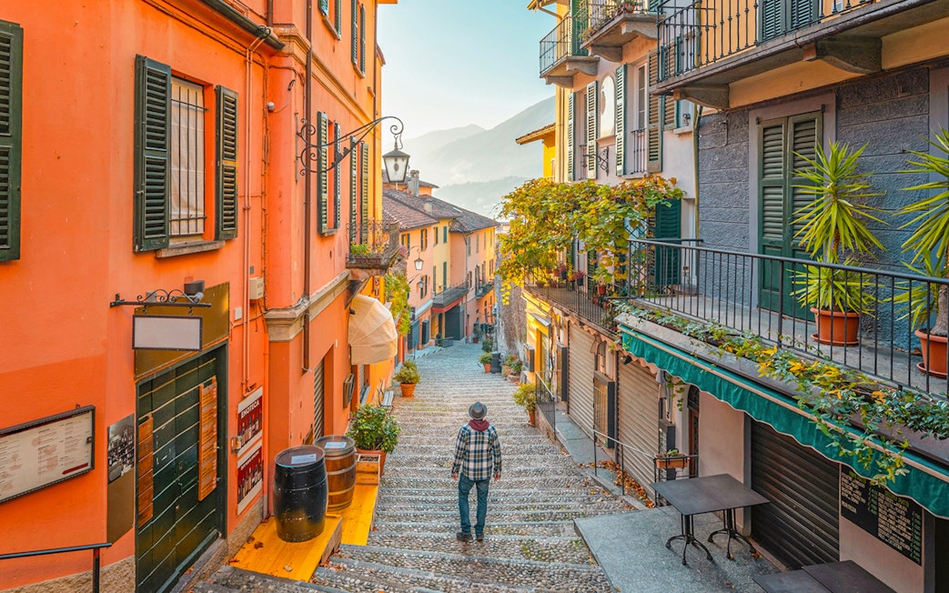 Narrow cobblestone street in Bellagio, Italy, with colorful buildings and a view of Lake Como.