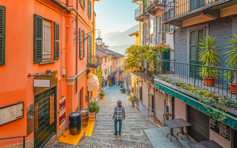 Narrow cobblestone street in Bellagio, Italy, with colorful buildings and a view of Lake Como.