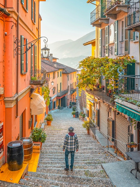 Narrow cobblestone street in Bellagio, Italy, with colorful buildings and a view of Lake Como.