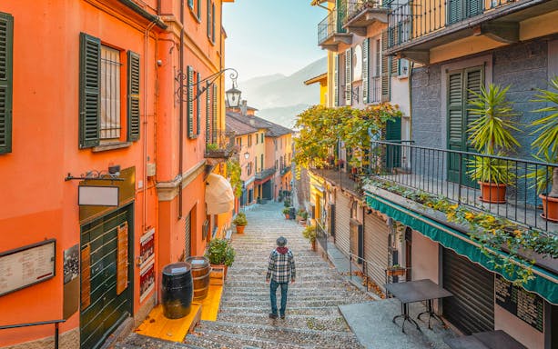 Narrow cobblestone street in Bellagio, Italy, with colorful buildings and a view of Lake Como.