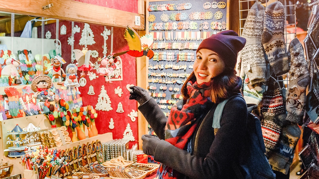 Shopper at Prague Christmas market browsing handmade ornaments.