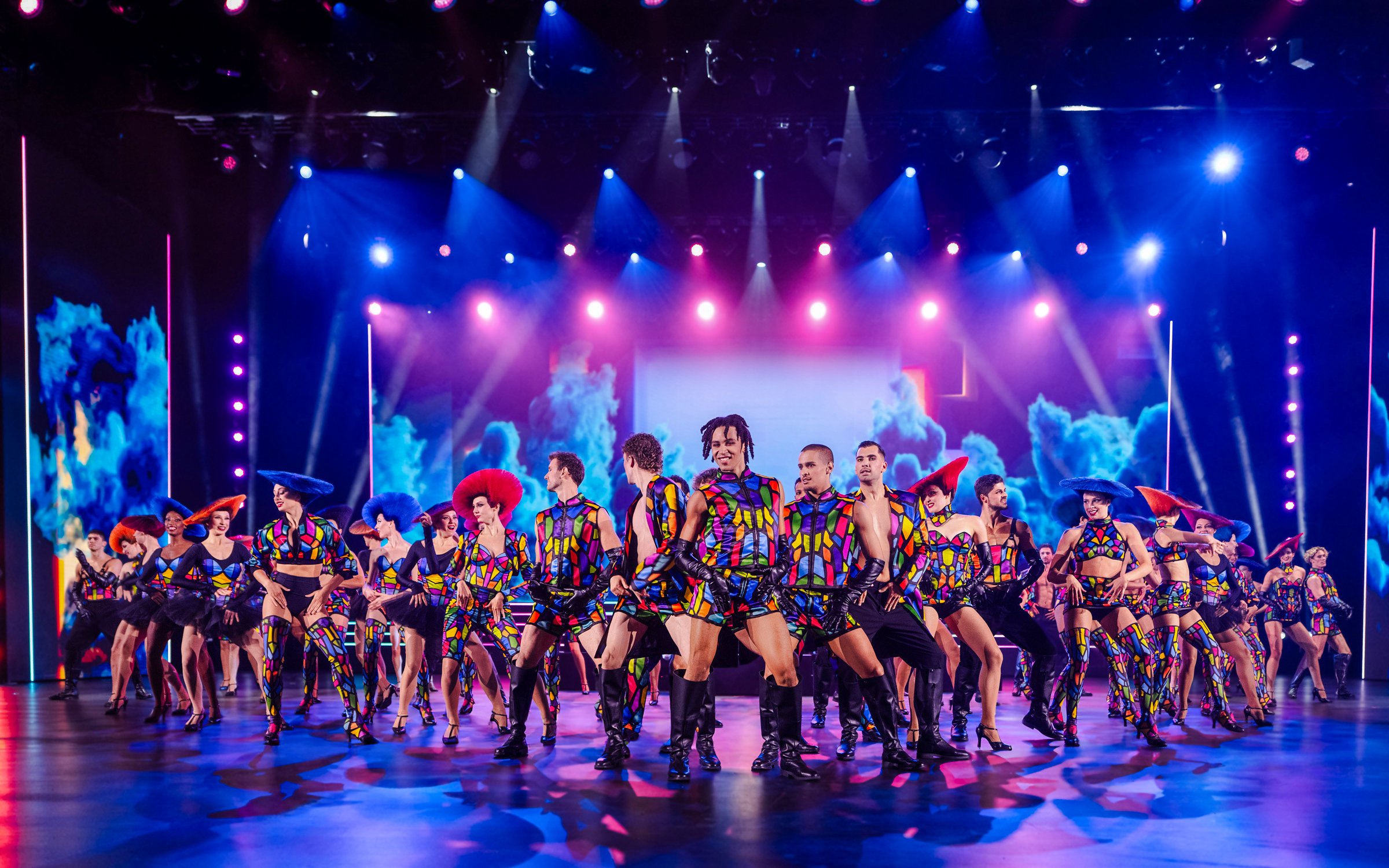 Performers in colorful costumes dancing on stage at Friedrichstadt Palast, Berlin.