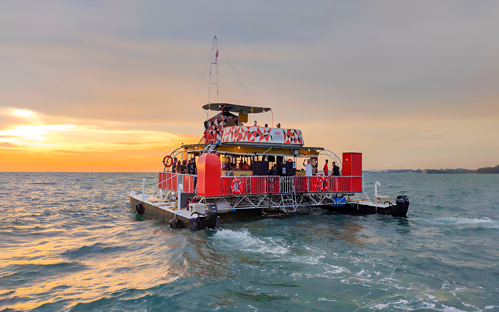 Catamaran on Dragon Sunset Cruise with passengers enjoying ocean view.