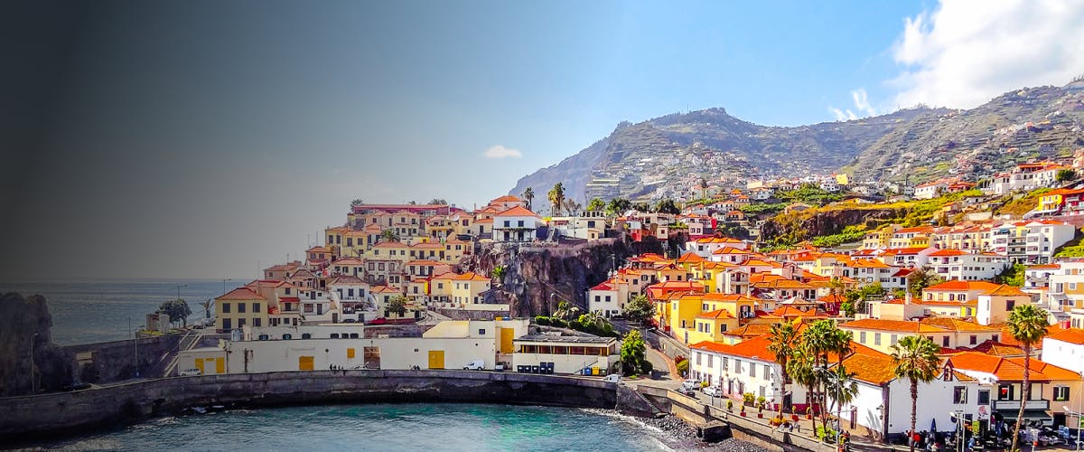 Funchal coastal view with colorful hillside houses and ocean backdrop, Portugal.