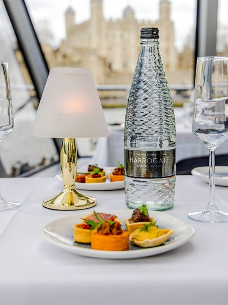 Dinner table setup on Thames River cruise with appetizers and water bottle.