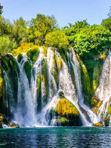Kravica Waterfall cascading over lush greenery on Trebizat River, Bosnia.