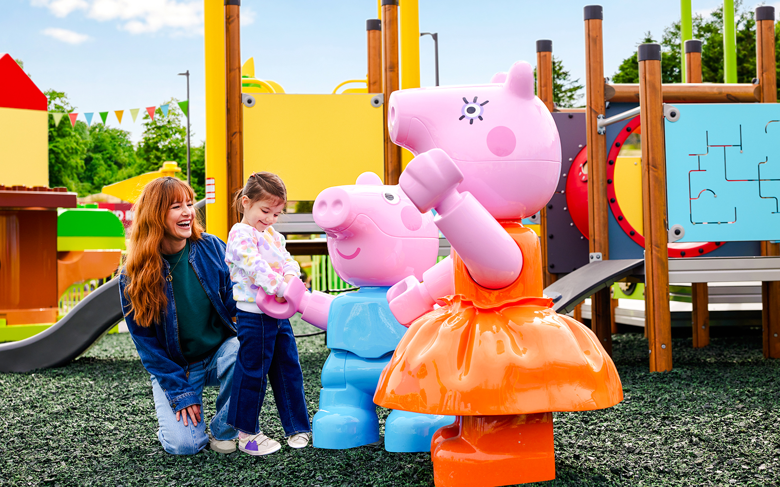 Child interacting with Peppa Pig statues at Legoland New York playground.