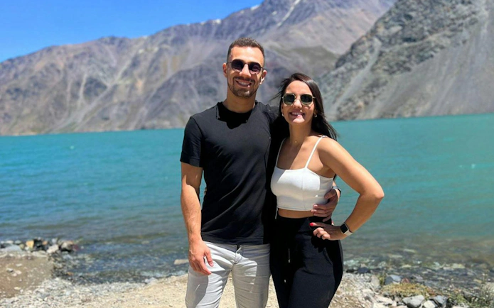 Couple by Embalse El Yeso in Cajon del Maipo, Santiago with mountains in the background.