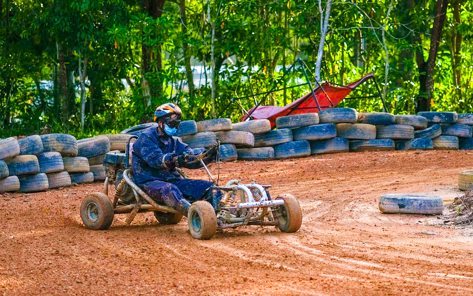 Go-kart driver navigating dirt track at Batam Adventure Park.
