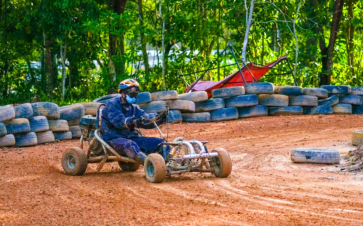 Go-kart driver navigating dirt track at Batam Adventure Park.