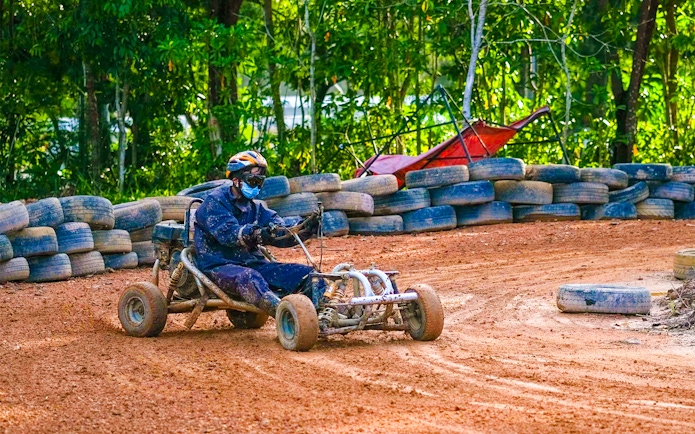 Go-kart driver navigating dirt track at Batam Adventure Park.