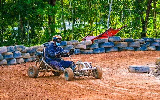 Go-kart driver navigating dirt track at Batam Adventure Park.