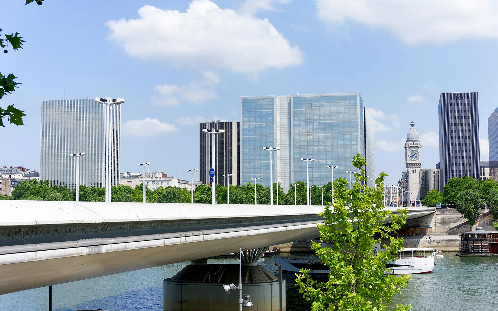 Charles de Gaulle Bridge over Seine River with Paris cityscape and clock tower.